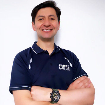 Personal trainer Jorge standing with arms folded and smiling wearing a navy blue shirt branded with Inner West Aquatics logo